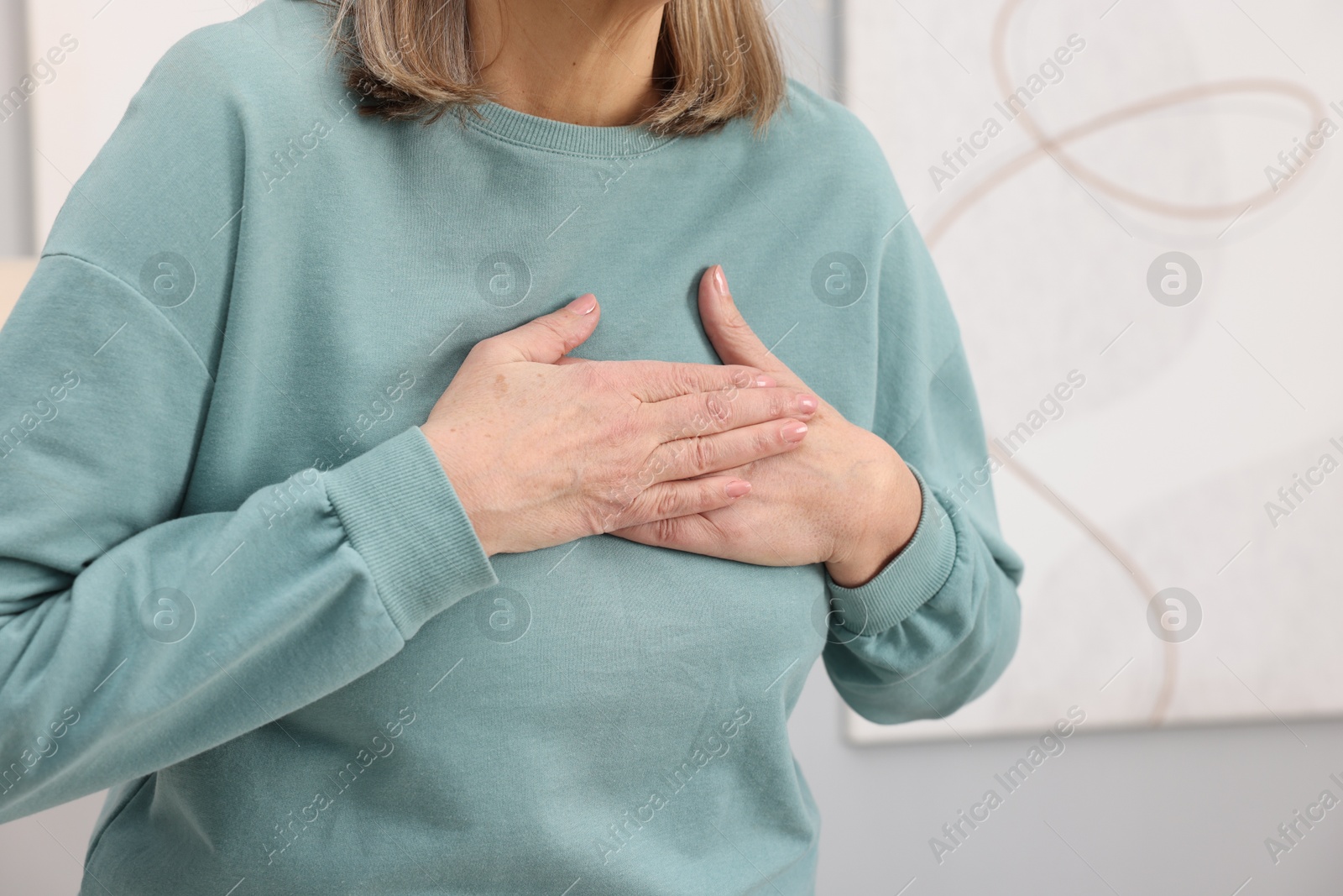 Photo of Heart attack. Senior woman suffering from pain in chest indoors, closeup