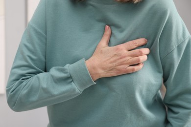 Photo of Heart attack. Senior woman suffering from pain in chest indoors, closeup