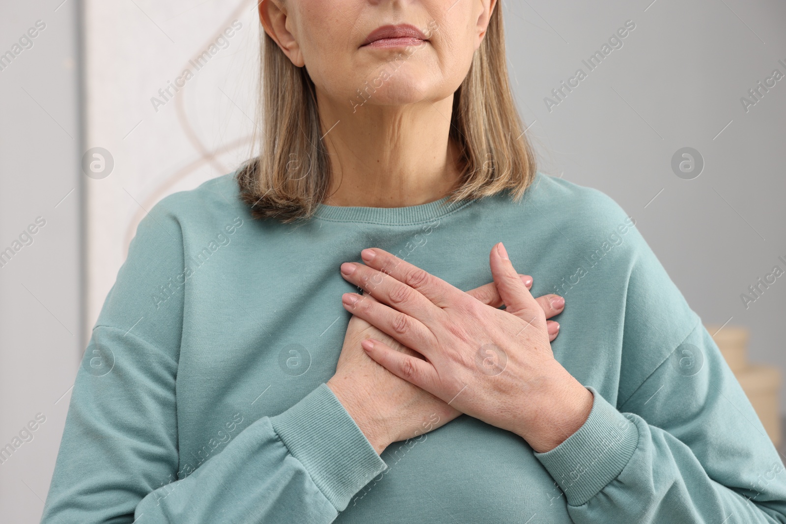 Photo of Heart attack. Senior woman suffering from pain in chest indoors, closeup