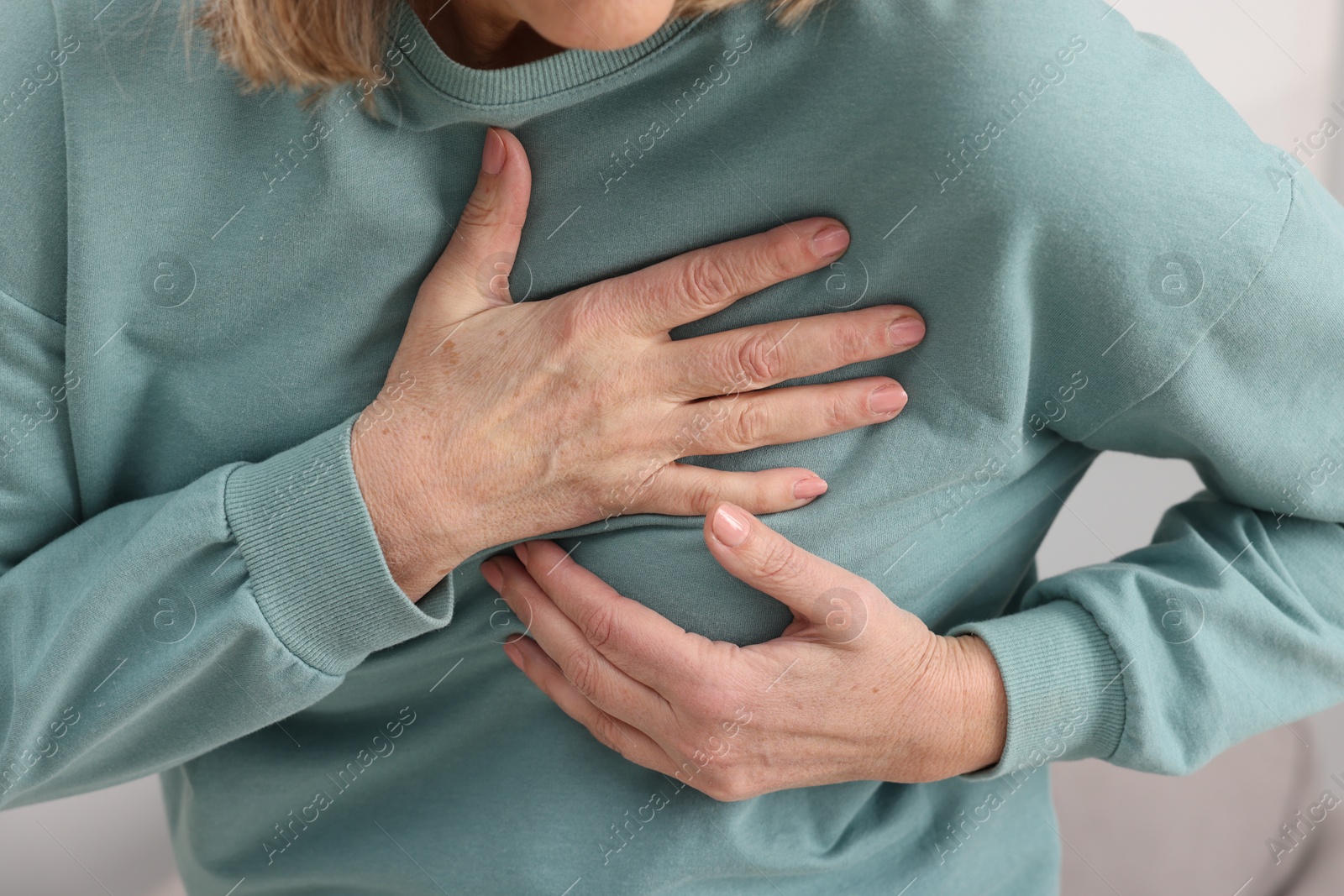 Photo of Heart attack. Senior woman suffering from pain in chest indoors, closeup