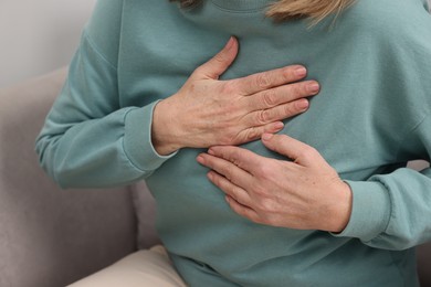 Photo of Heart attack. Senior woman suffering from pain in chest indoors, closeup