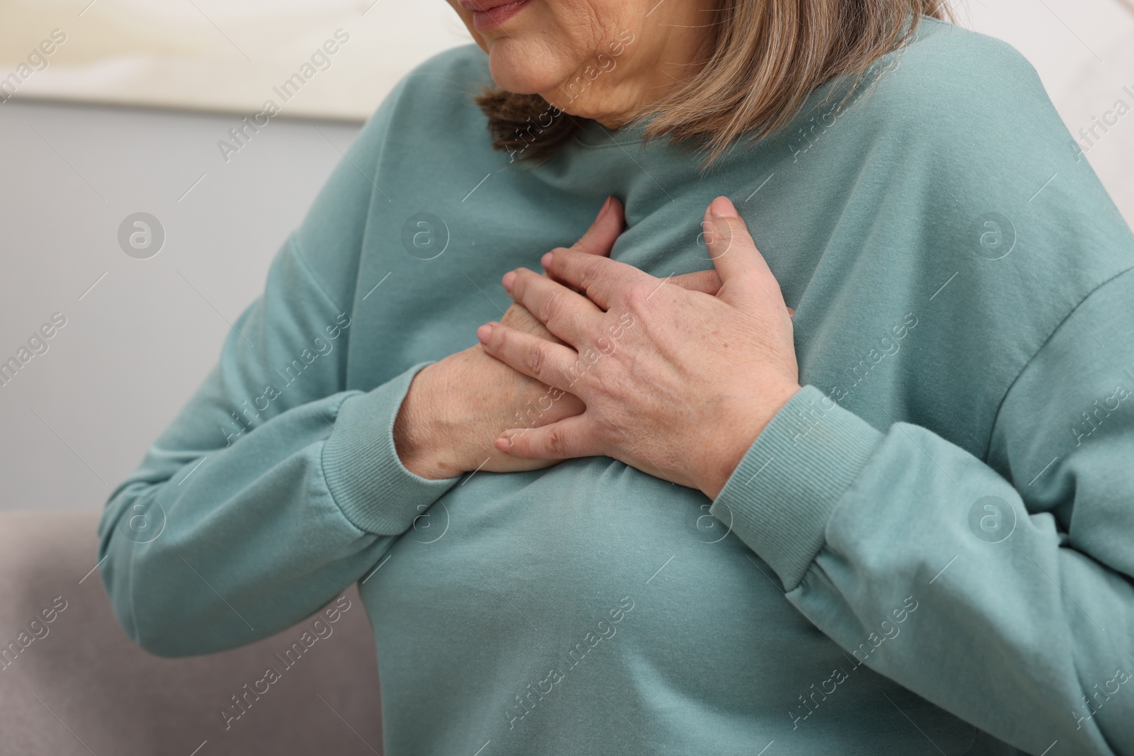 Photo of Heart attack. Senior woman suffering from pain in chest indoors, closeup