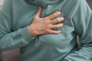 Photo of Heart attack. Senior woman suffering from pain in chest indoors, closeup