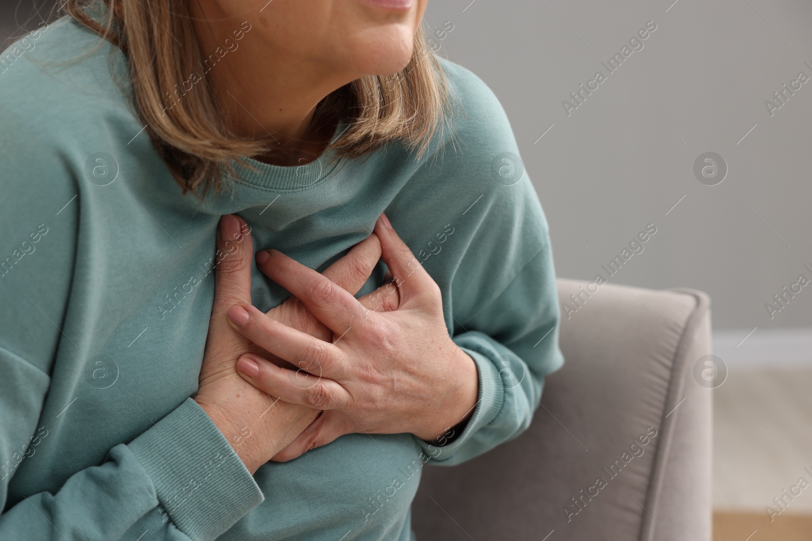 Photo of Heart attack. Senior woman suffering from pain in chest indoors, closeup