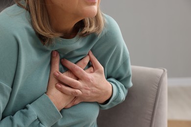 Photo of Heart attack. Senior woman suffering from pain in chest indoors, closeup