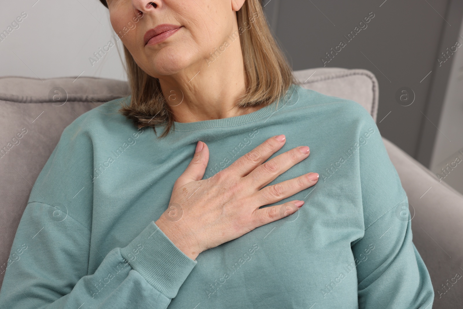 Photo of Heart attack. Senior woman suffering from pain in chest indoors, closeup