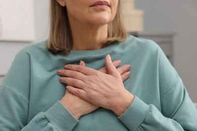 Photo of Heart attack. Senior woman suffering from pain in chest indoors, closeup