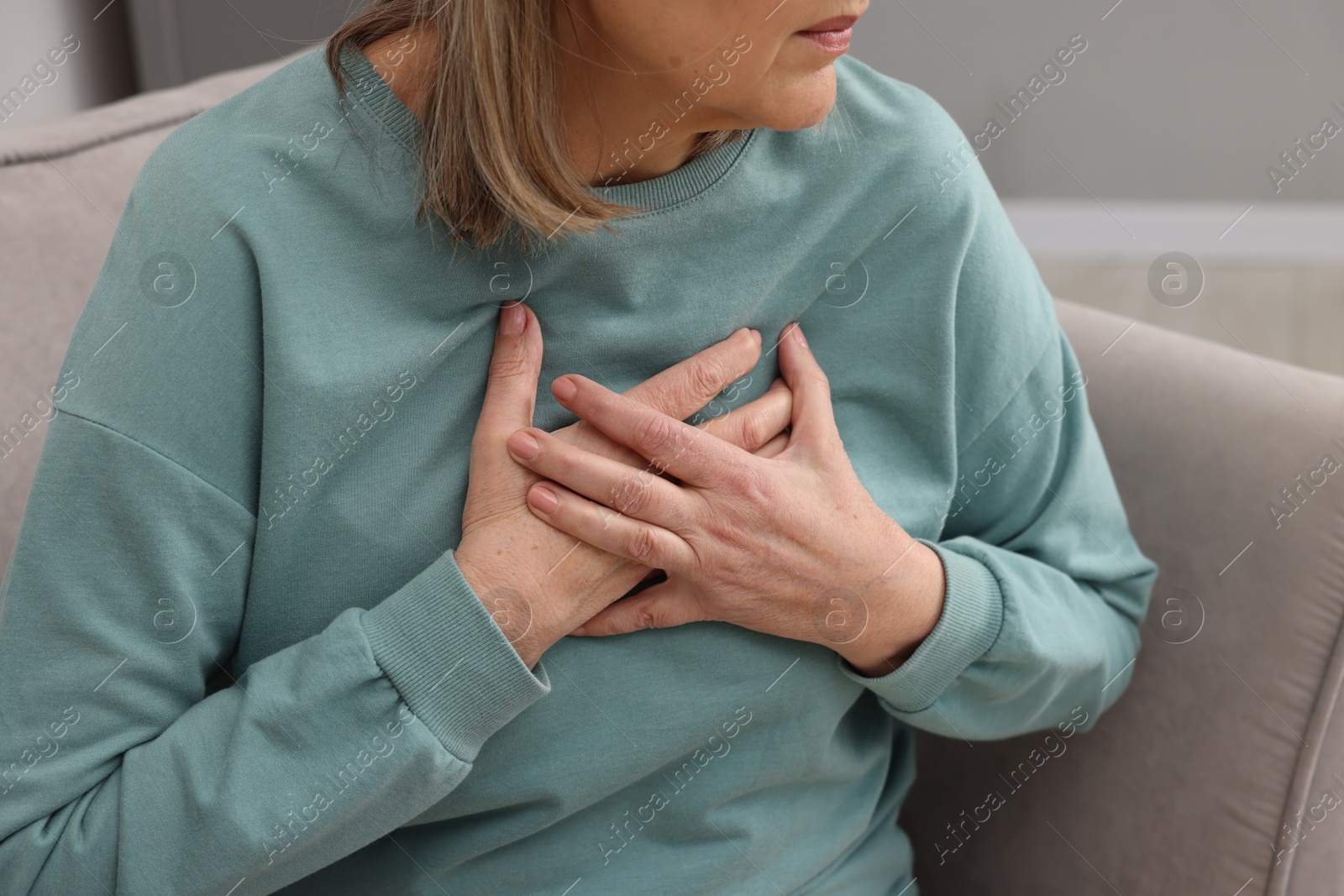 Photo of Heart attack. Senior woman suffering from pain in chest indoors, closeup