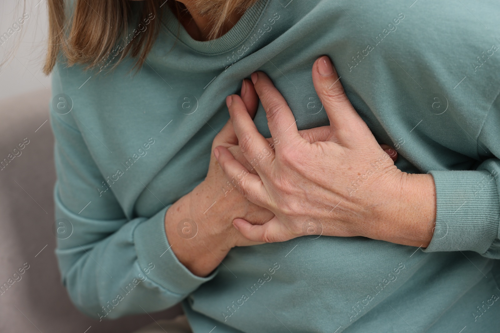 Photo of Heart attack. Senior woman suffering from pain in chest indoors, closeup