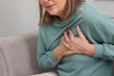 Photo of Heart attack. Senior woman suffering from pain in chest indoors, closeup