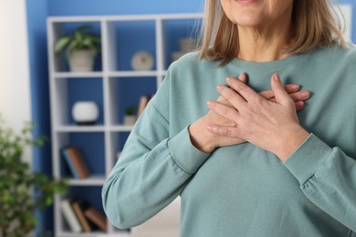 Photo of Heart attack. Senior woman suffering from pain in chest indoors, closeup