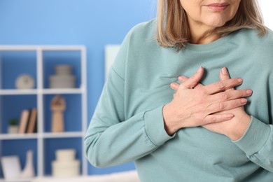 Photo of Heart attack. Senior woman suffering from pain in chest indoors, closeup