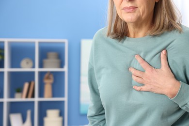 Photo of Heart attack. Senior woman suffering from pain in chest indoors, closeup. Space for text