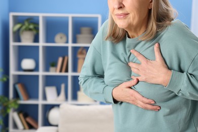 Photo of Heart attack. Senior woman suffering from pain in chest indoors, closeup. Space for text