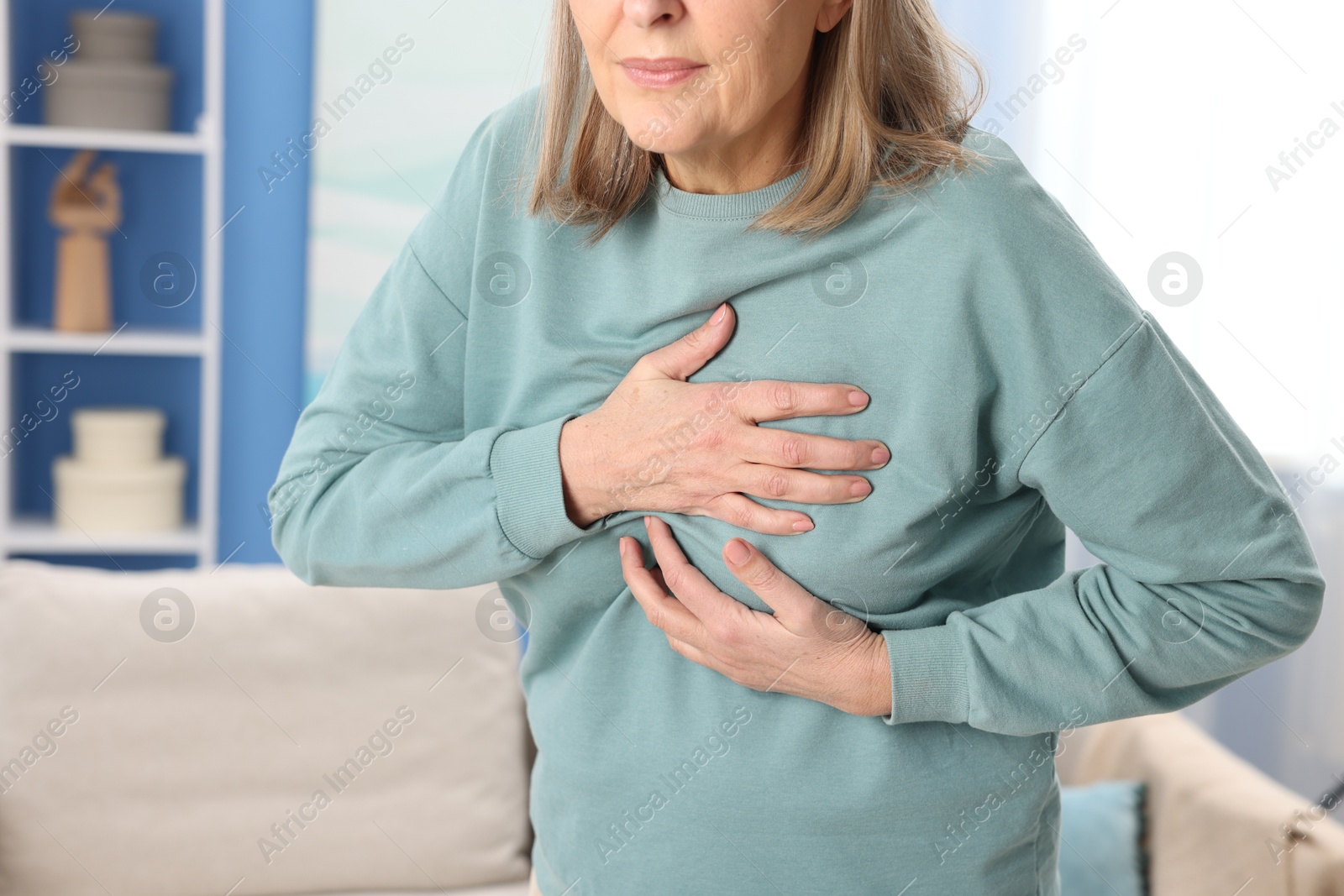 Photo of Heart attack. Senior woman suffering from pain in chest indoors, closeup