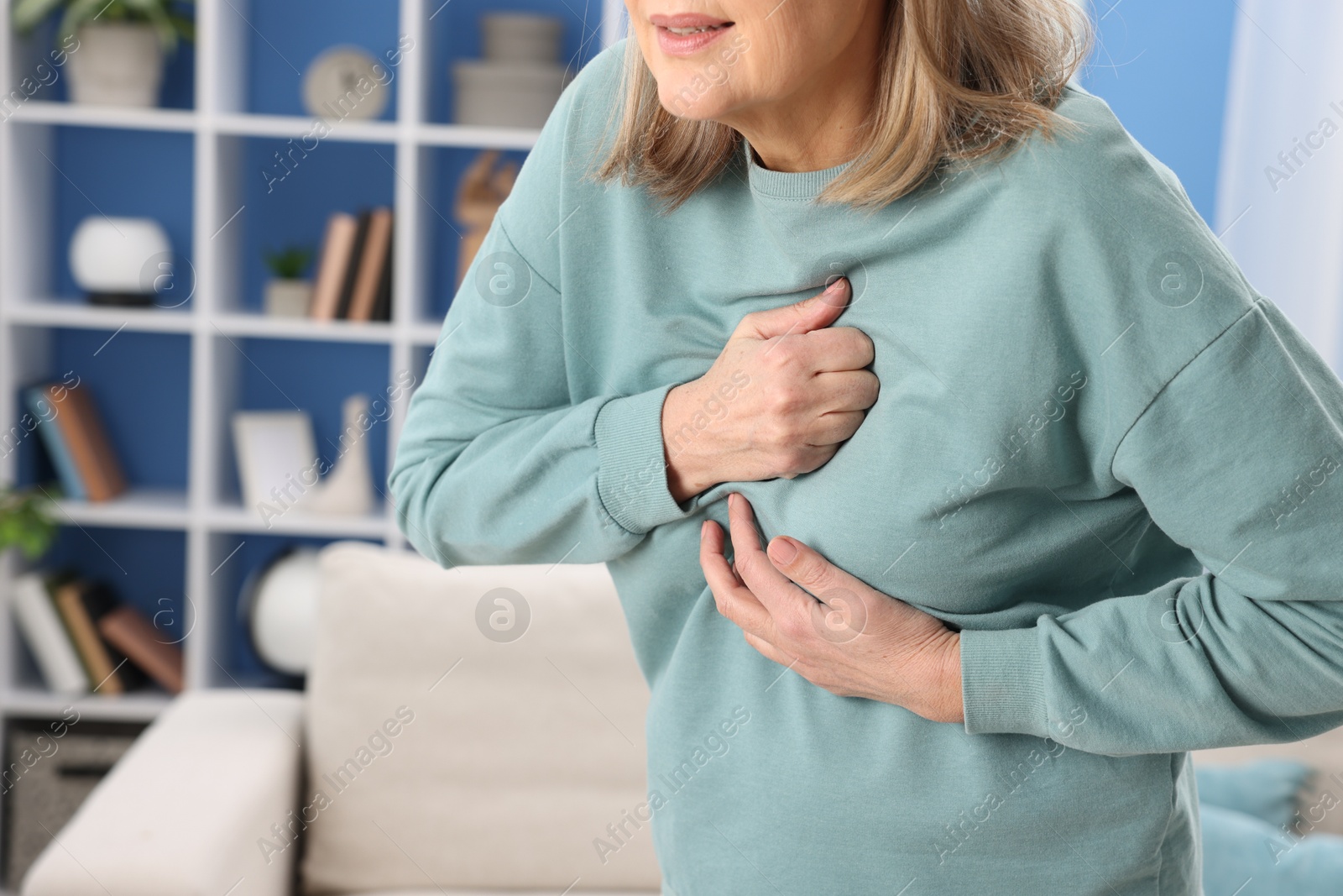 Photo of Heart attack. Senior woman suffering from pain in chest indoors, closeup