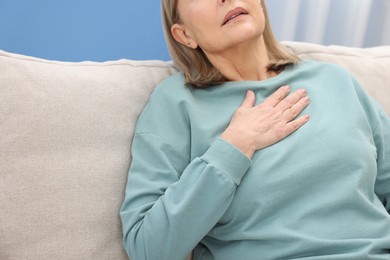 Photo of Heart attack. Senior woman suffering from pain in chest indoors, closeup