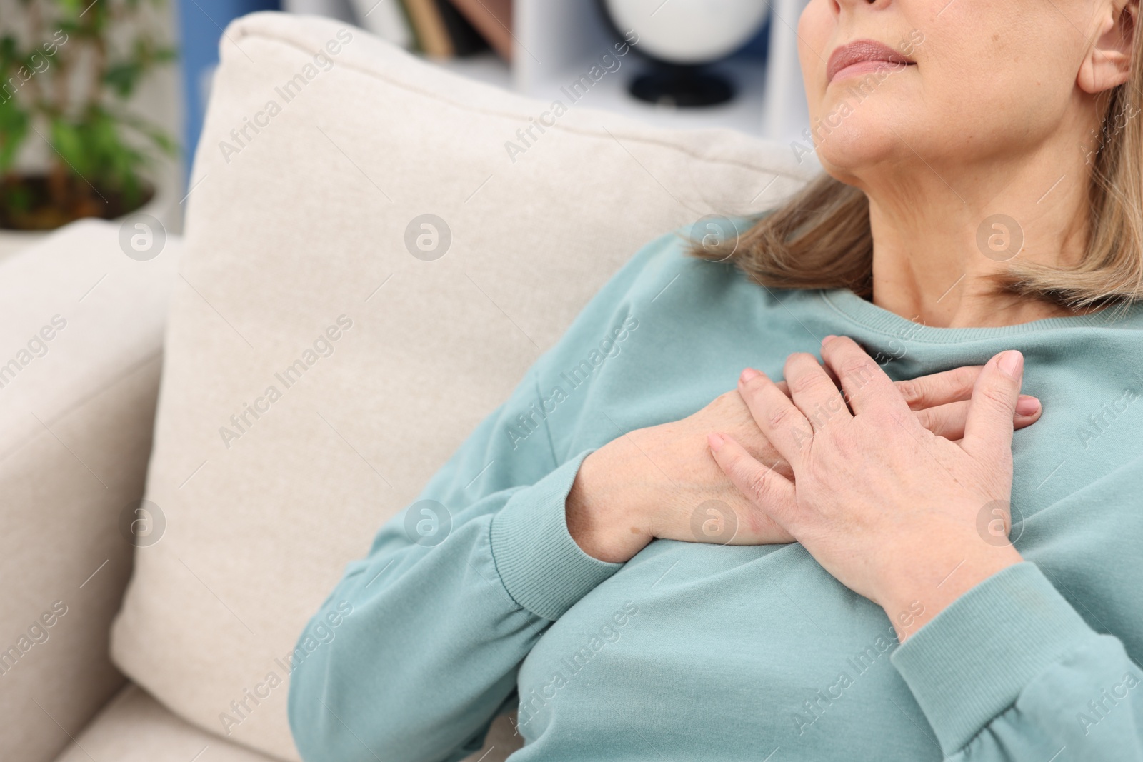 Photo of Heart attack. Senior woman suffering from pain in chest indoors, closeup