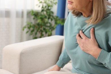 Photo of Heart attack. Senior woman suffering from pain in chest indoors, closeup. Space for text