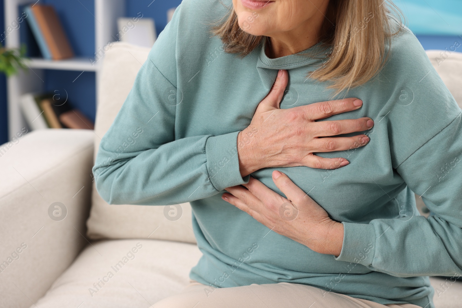 Photo of Heart attack. Senior woman suffering from pain in chest indoors, closeup