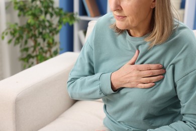 Photo of Heart attack. Senior woman suffering from pain in chest indoors, closeup. Space for text