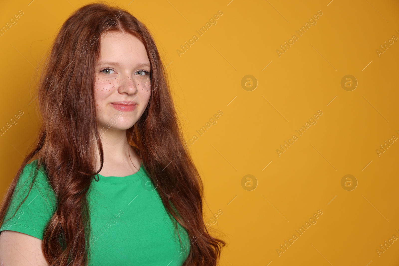 Photo of Beautiful teenage girl with freckles on orange background, space for text