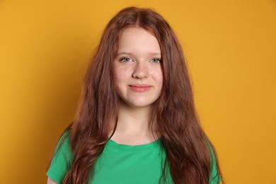 Beautiful teenage girl with freckles on orange background