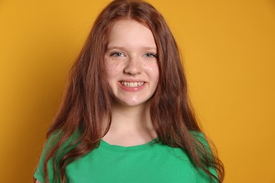 Photo of Beautiful teenage girl with freckles on orange background