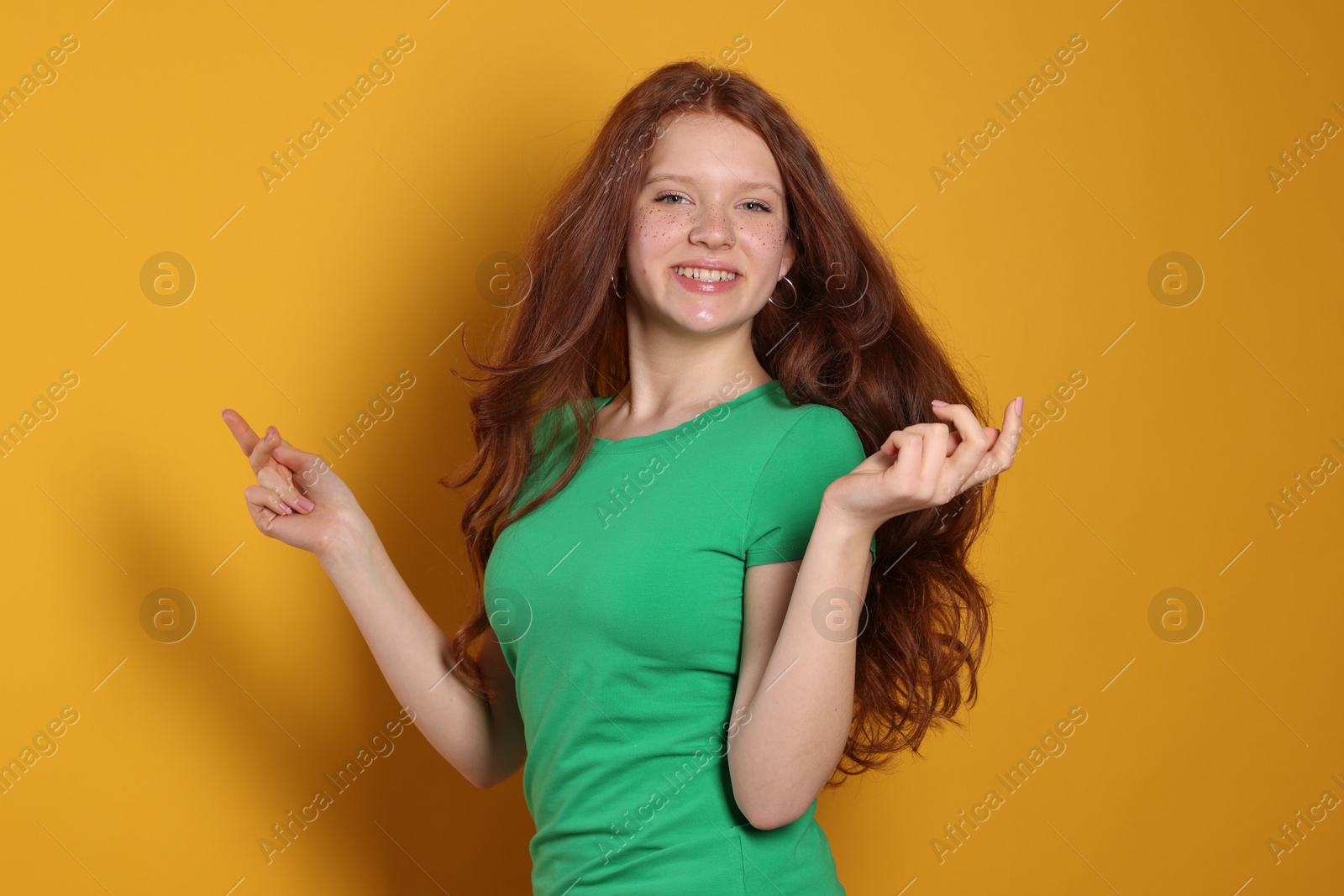 Photo of Beautiful teenage girl with freckles on orange background