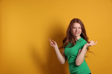 Photo of Beautiful teenage girl with freckles on orange background, space for text