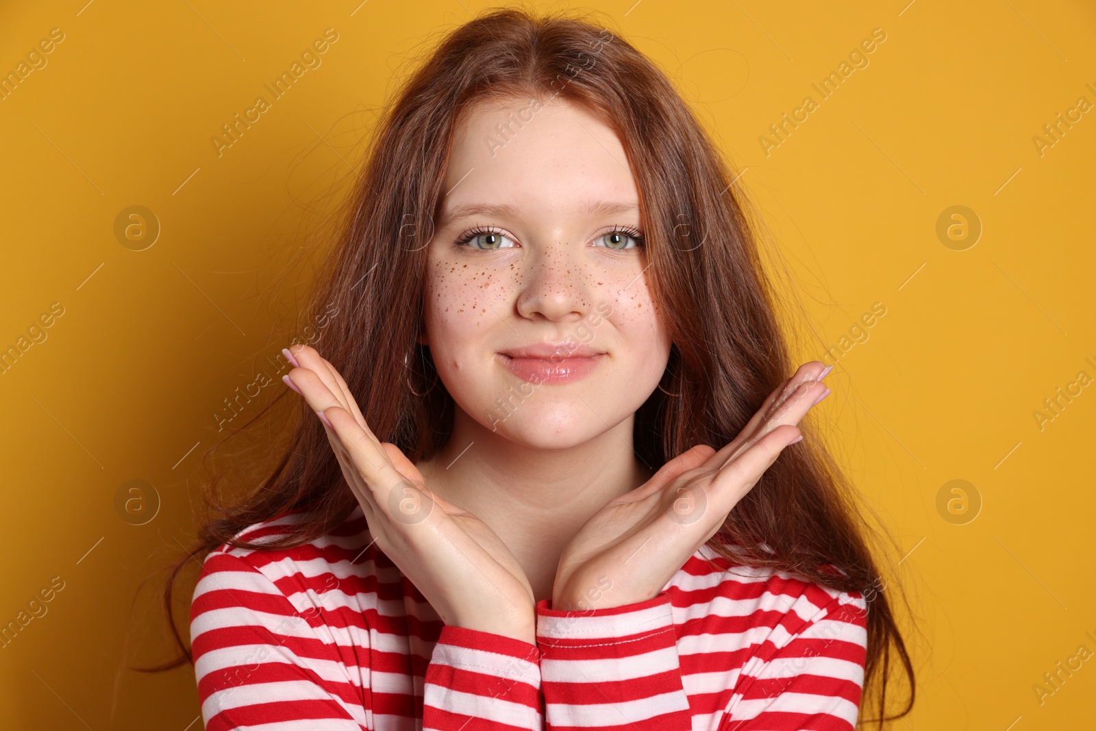 Photo of Beautiful teenage girl with freckles on orange background