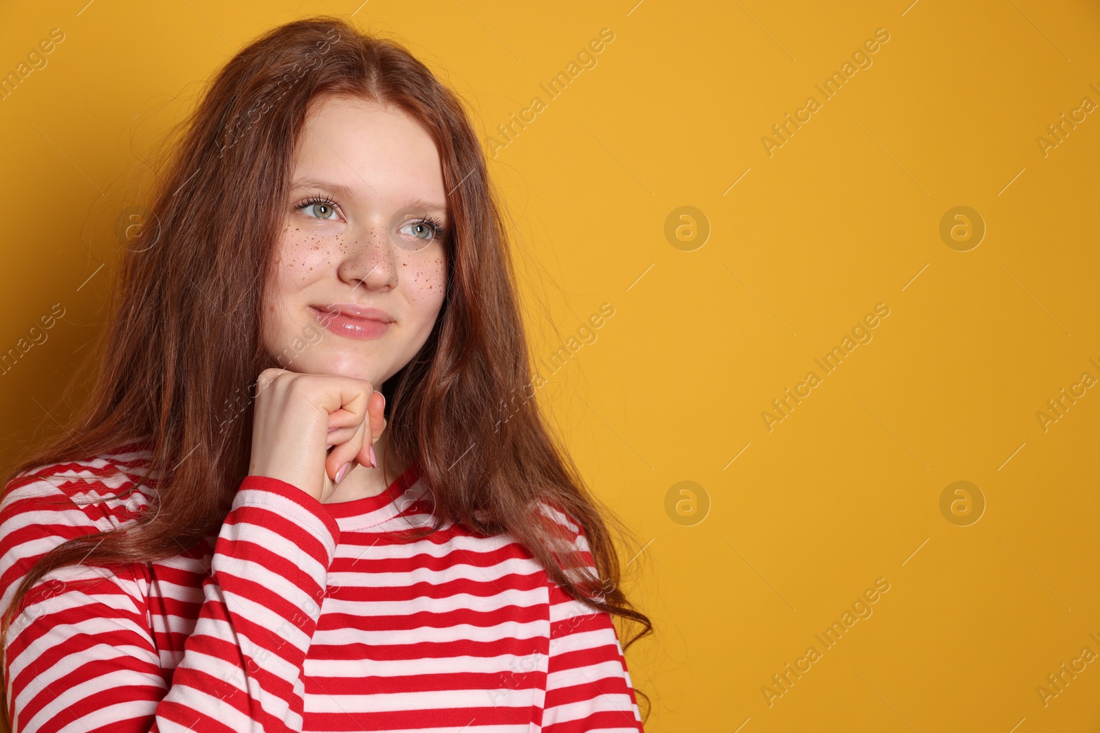 Photo of Beautiful teenage girl with freckles on orange background, space for text