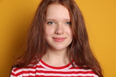 Beautiful teenage girl with freckles on orange background