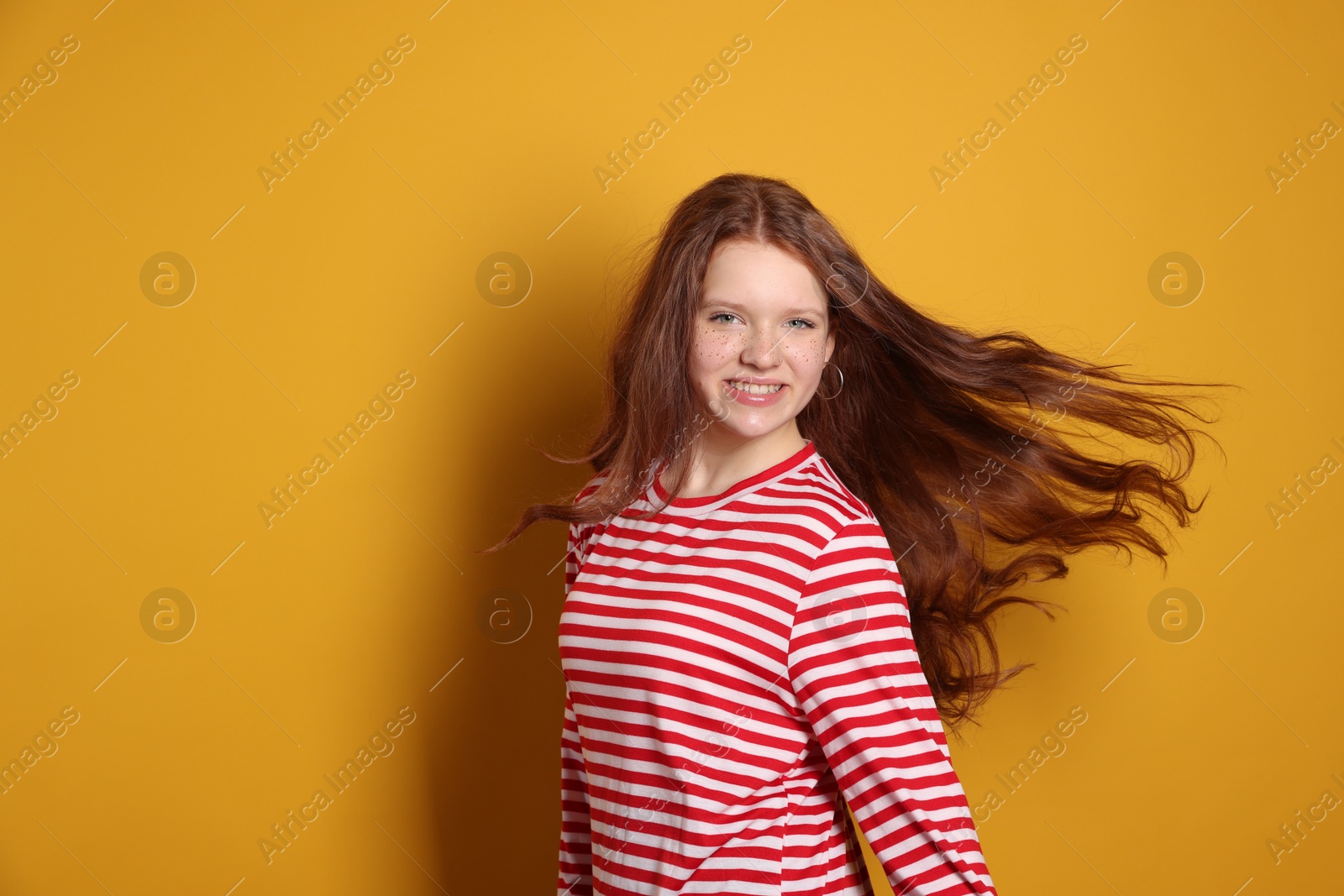 Photo of Beautiful teenage girl with freckles on orange background, space for text