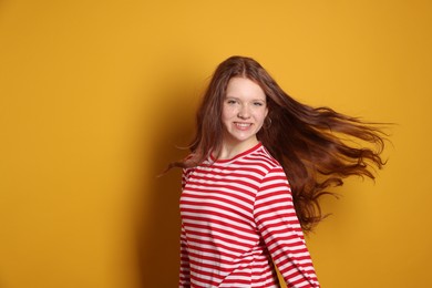 Beautiful teenage girl with freckles on orange background, space for text