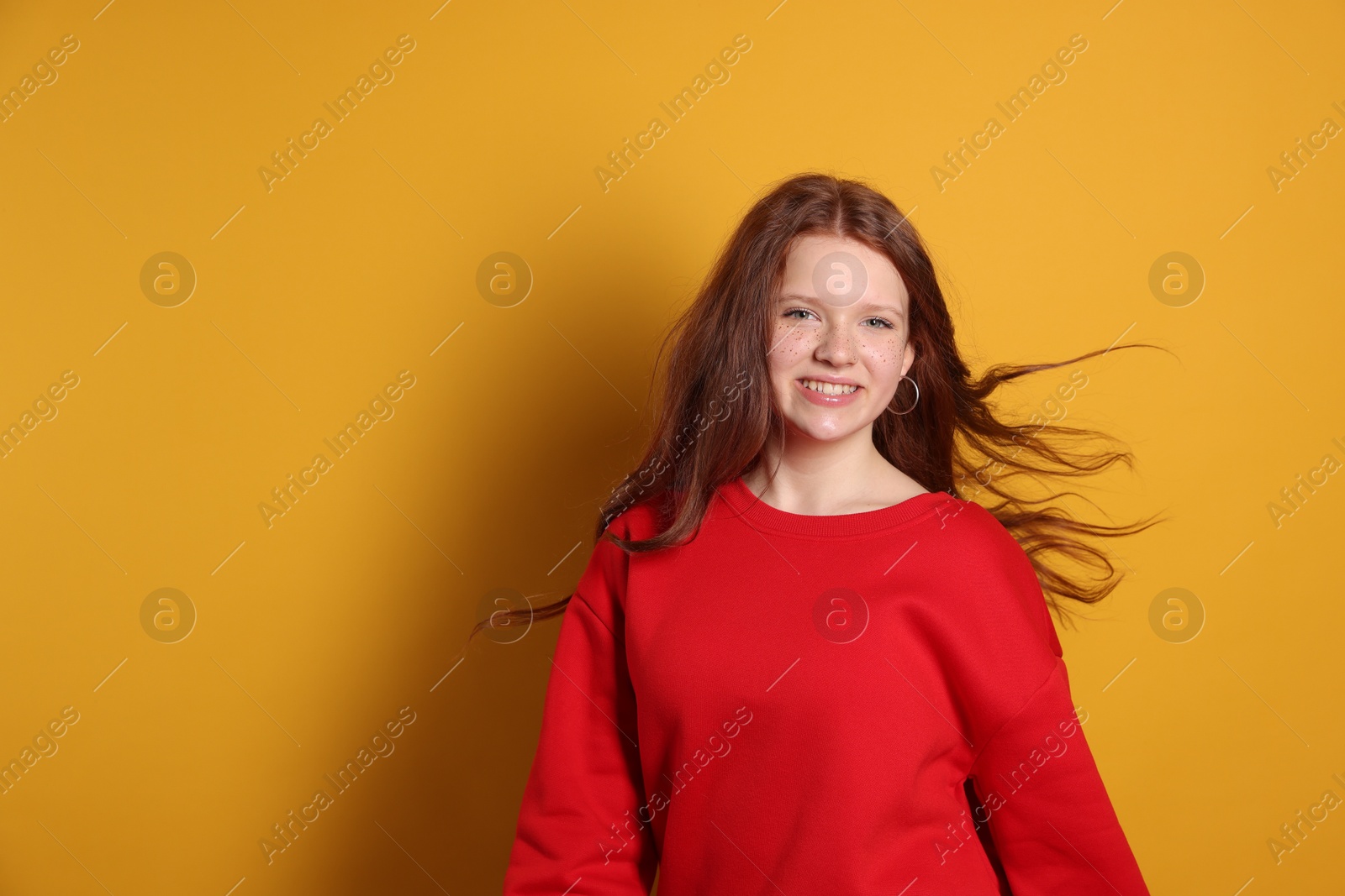 Photo of Beautiful teenage girl with freckles on orange background, space for text