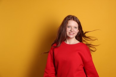 Photo of Beautiful teenage girl with freckles on orange background, space for text