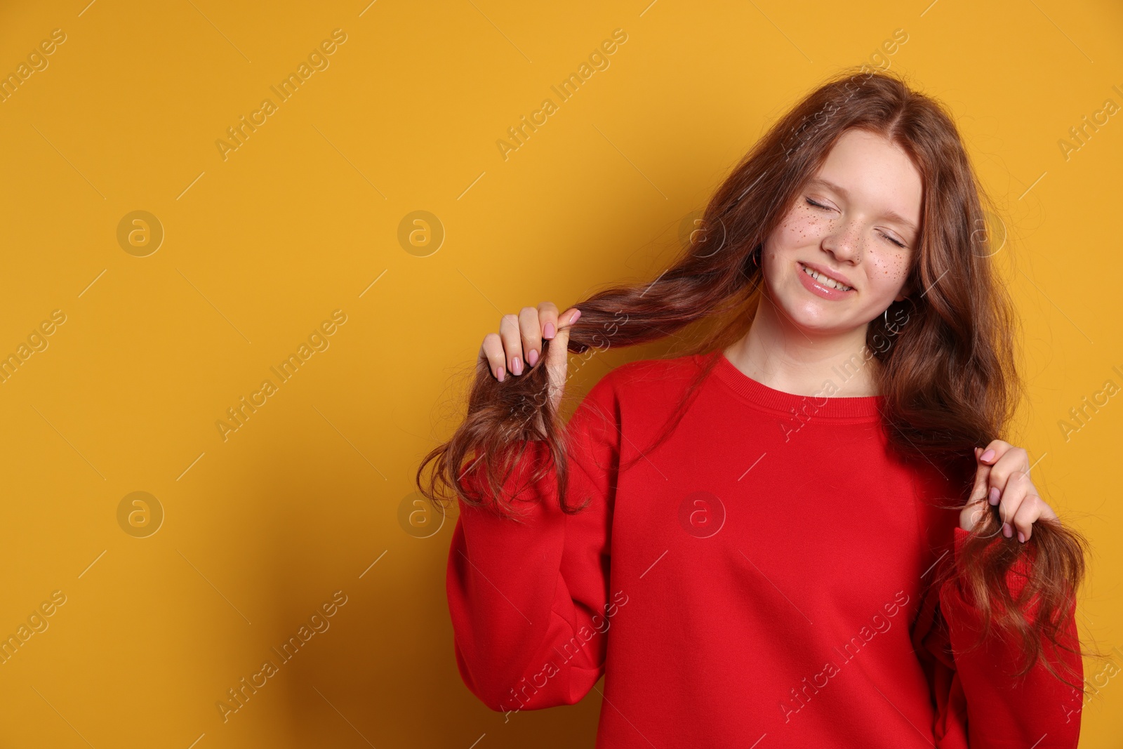 Photo of Beautiful teenage girl with freckles on orange background, space for text