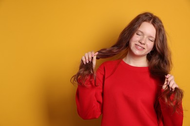 Beautiful teenage girl with freckles on orange background, space for text