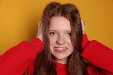 Beautiful teenage girl with freckles on orange background