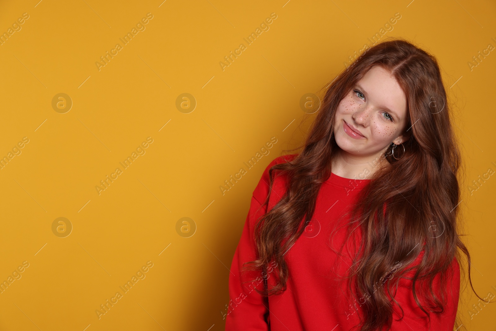 Photo of Beautiful teenage girl with freckles on orange background, space for text