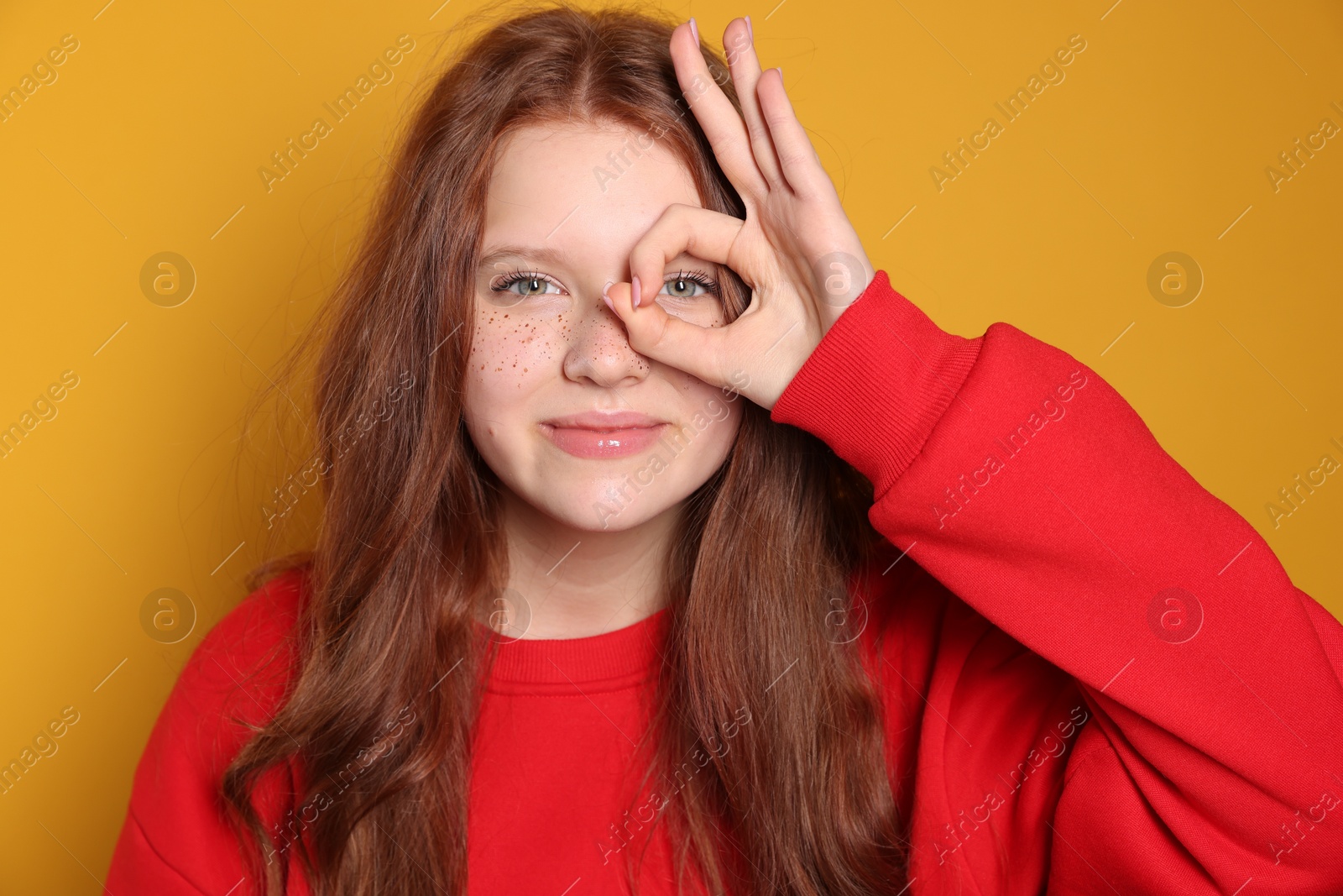 Photo of Beautiful teenage girl with freckles on orange background