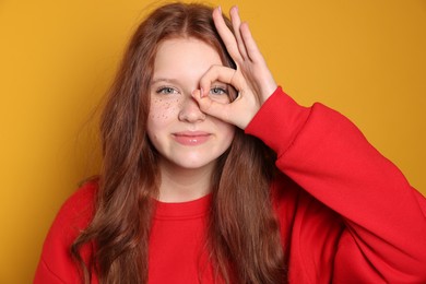 Beautiful teenage girl with freckles on orange background