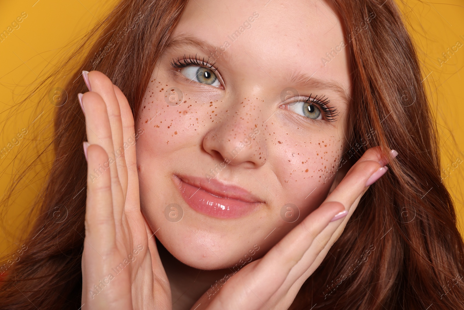 Photo of Beautiful teenage girl with freckles on orange background, closeup