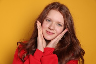 Beautiful teenage girl with freckles on orange background