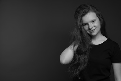 Photo of Beautiful teenage girl with freckles on dark background, space for text. Black and white effect