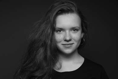 Beautiful teenage girl with freckles on dark background. Black and white effect