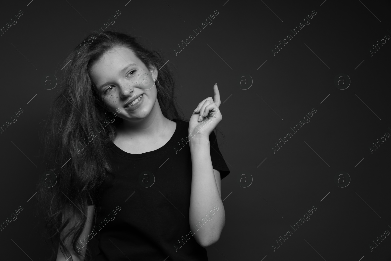 Photo of Beautiful teenage girl with freckles on dark background, space for text. Black and white effect