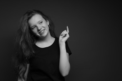 Photo of Beautiful teenage girl with freckles on dark background, space for text. Black and white effect