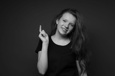 Photo of Beautiful teenage girl with freckles on dark background. Black and white effect